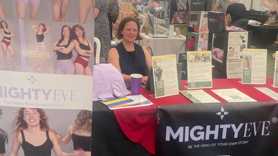 The Mighty Eve stand in the Made in Herts Marquee, Hertfordshire County Show, with the product range, customer persona cards on the table, and the Be the Hero of Your Own Story banner.