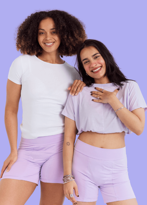 underwear for perimenopause - Night Period Shorts - postpartum - Two women wearing matching white t-shirts and lavender shorts against a purple background