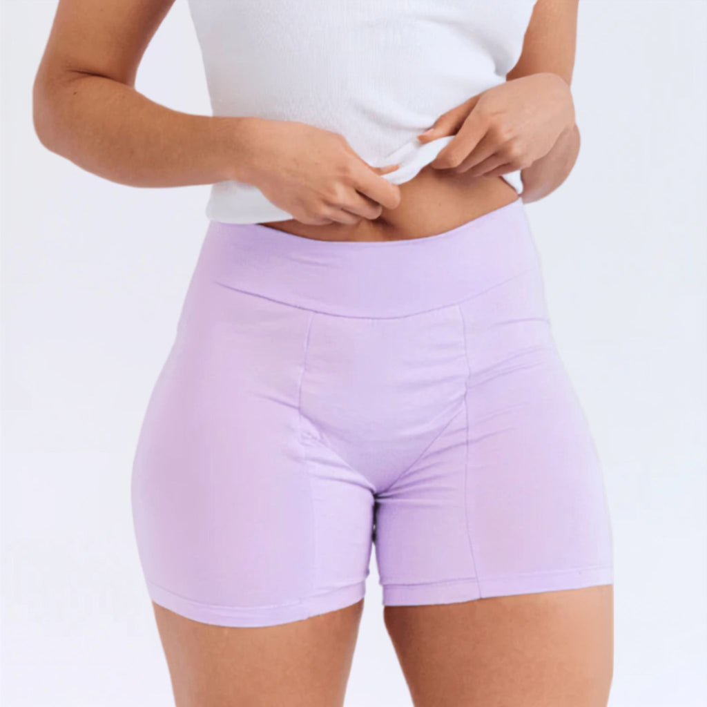 A model wearing light purple high-waisted period shorts and a white ribbed crop top, shown from the chest down against a plain white studio background.