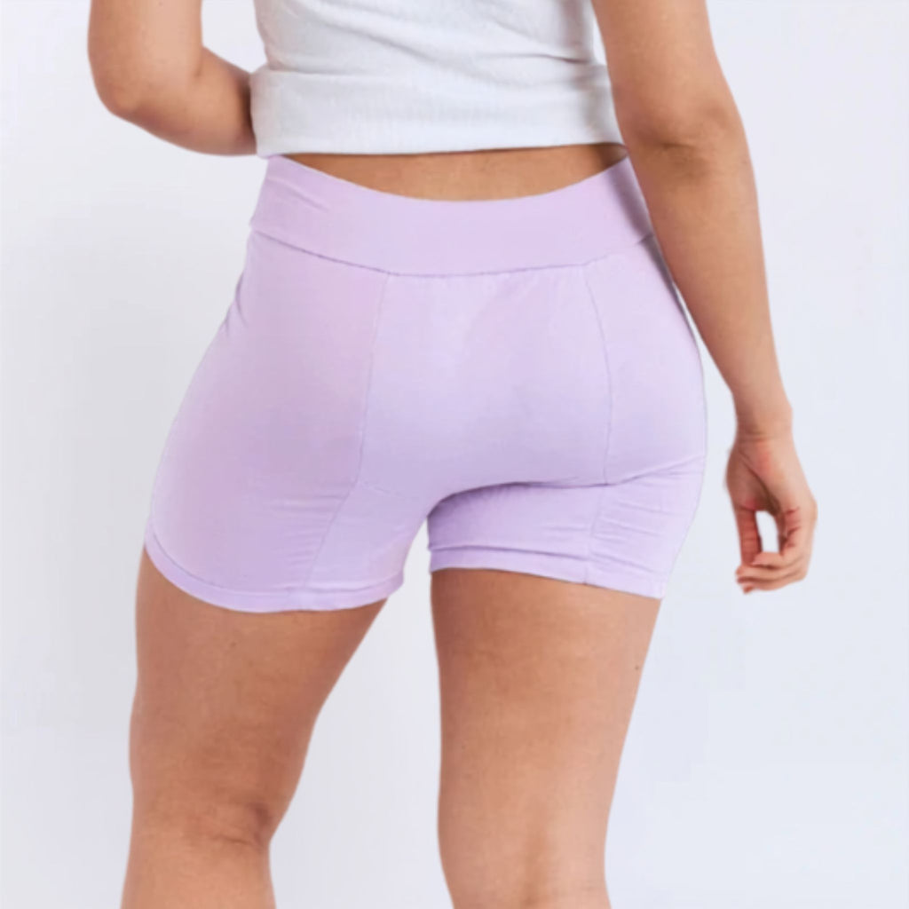 A model wearing light purple high-waisted period  shorts, shown from a rear three-quarter angle against a plain white background.