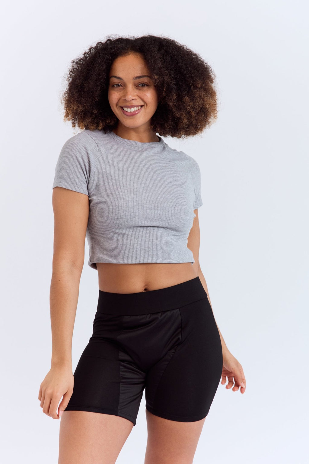 Mighty Gusher Period Shorts - MightyEve GSS01 Woman wearing a gray crop top and black period shorts on a white background