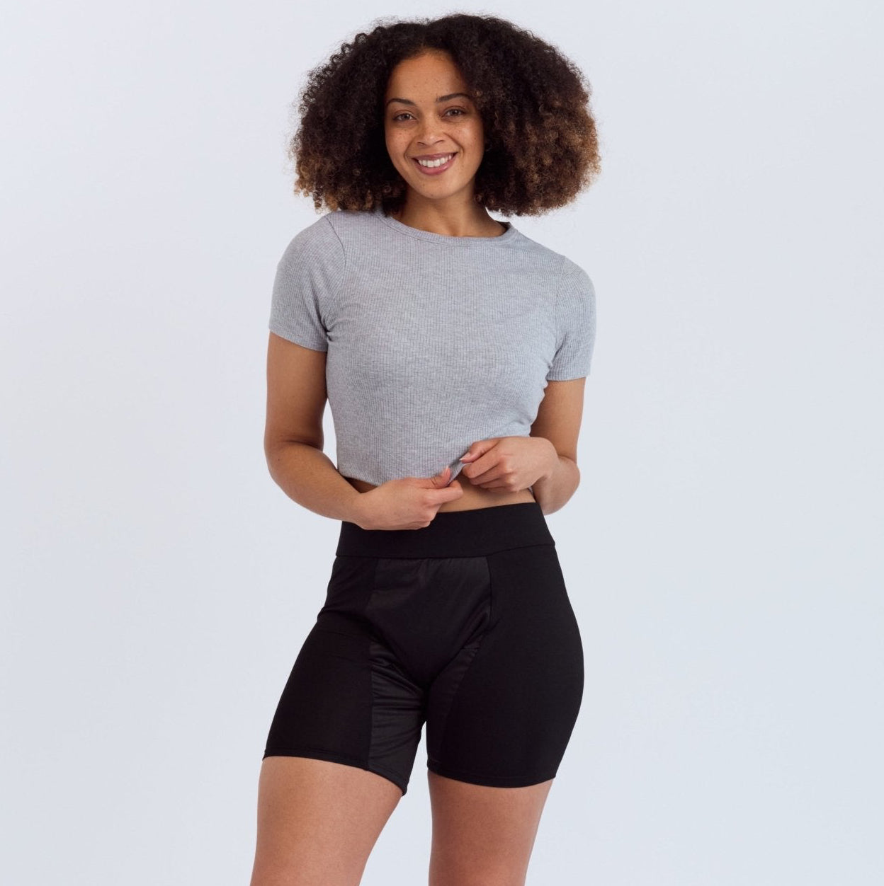 Mighty Gusher Period Shorts - MightyEve GSS01 Woman wearing a gray t-shirt and black period shorts on a white background
