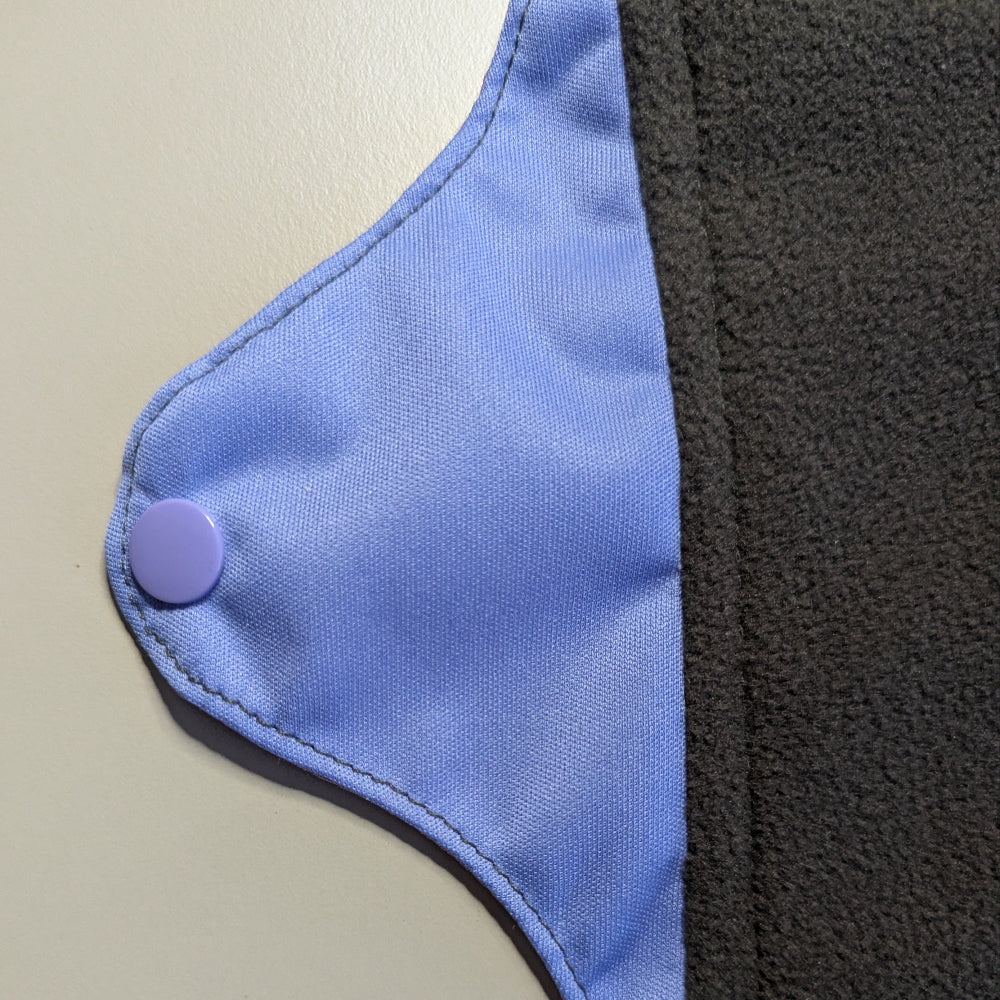 Close-up of a mighty eve period pad with popper closure on a light background.