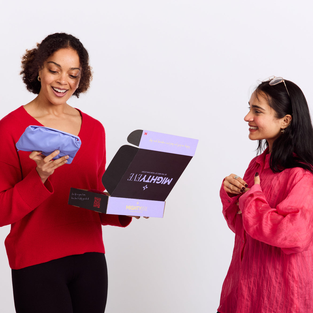 Two women holding and looking at a mightyEve branded product against a white background