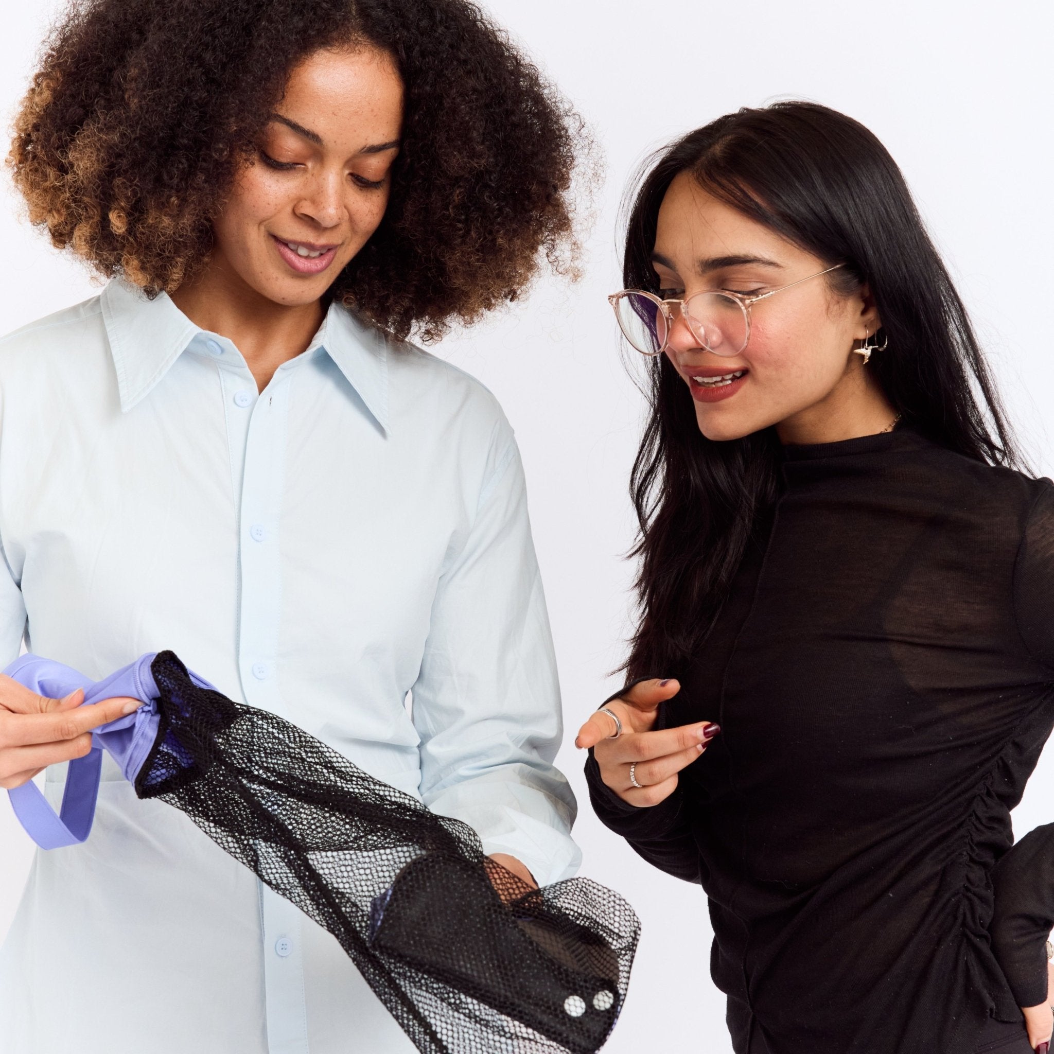 New Membership Offer - MightyEve  Two women looking at a black mesh wash clutch bag on a white background